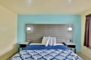 Un dormitorio azul con una cama con dos sillas. en Americas Best Value Inn San Antonio Airport South, en San Antonio