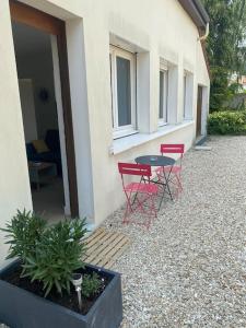 a patio with red chairs and a table in front of a building at T2 spacieux avec baignoire Balnéo en RdC sur cour in Saint-Florentin