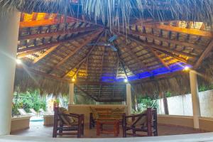 a wooden table and chairs under a straw umbrella at Villa Infinito Bani's Exclusive Beachside Mansion in Baní