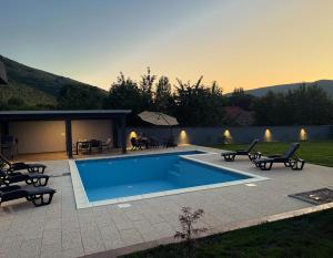 a swimming pool in a yard with chairs and a patio at House and pool BajNa in Mostar