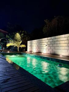 a swimming pool at night with a brick wall at Rosatrip Surf Bungalows in Praia do Rosa