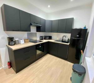 a kitchen with black cabinets and a black refrigerator at Grande Maison de ville idéale pour se réunir in Saint-Florentin