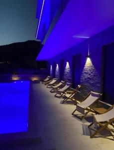 a row of lounge chairs next to a swimming pool at night at Kabaseo Spa in Becici
