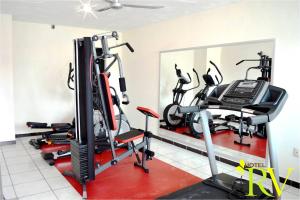 een fitnessruimte met loopbanden, crosstrainers en een spiegel bij Hotel RV in Martínez de La Torre