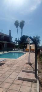 una piscina accanto a un resort con palme di Hacienda el chorlo a Encinarejo De Córdoba
