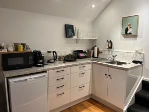 a white kitchen with a sink and a microwave at The Greytown Loft in Greytown