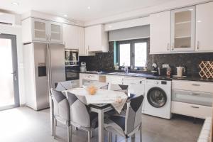 a white kitchen with a table and chairs and a dishwasher at Vivenda à Beira Rio in Folgosa