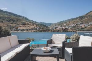 a patio with chairs and a table and a lake at Vivenda à Beira Rio in Folgosa