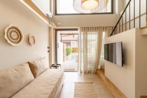 a living room with a couch and a tv at ADORNO PRIVATE SUITES Only Adults & Kids 12 Plus in Nea Vrasna