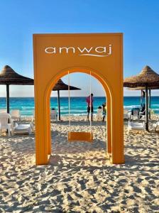 エル・アラメインにあるAmwaj الساحل الشمالىの浜辺のオレンジ色の看板(椅子、パラソル付)