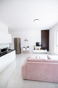 un soggiorno con divano rosa e una cucina di Novostavba v centre + parking a Banská Bystrica