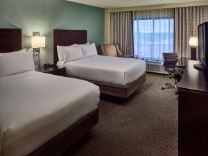 a hotel room with two beds and a desk at Sonesta Atlanta Airport North in Atlanta
