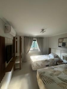a hotel room with two beds and a window at Venda Nova Apart in Venda Nova do Imigrante