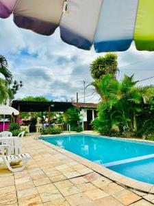 a swimming pool with two chairs and an umbrella at Pousada do Gord0 in Bonito