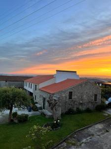 TouguesにあるO Celeiro - Espaço Ruralの夕暮れ時の赤い屋根の石造りの建物