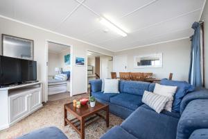 a living room with a blue couch and a tv at Blue View - UNINTERRUPTED OCEAN VIEWS FOR MILES in Guilderton