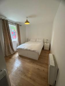 a white bedroom with a bed and a window at Paprika Nest in Hendon