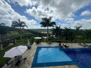 a swimming pool with chairs and umbrellas and trees at Apt Alto da Serra Villas - Bananeiras in Bananeiras