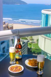 a table with two glasses of beer and food at Estanconfor Vista Mar comGaragem Arrumação Diária, Ar Cond. e Cozinha in Santos