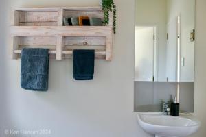 a bathroom with a sink and a toilet and a mirror at Mill Creek Cottage in Coroglen
