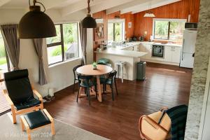 a kitchen with a table and chairs in a room at Mill Creek Cottage in Coroglen +30 photos