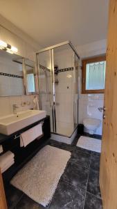 a bathroom with a sink and a shower and a toilet at Ferienwohnung Scandella Otto und Monika in Sent +3 photos