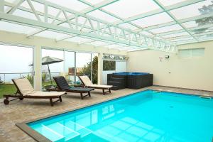 a swimming pool with two chairs and a table at Casa da Relva com Piscina Aquecida Interna in Arco da Calheta