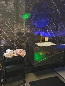 a black bathroom with a sink and a mirror at La Suite Gold Wellness Jacuzzi & Sauna in Seraing