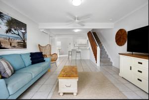 Una sala de estar con un sofá azul y un televisor. en Seychelles 2 - Short stroll to Noosa River, en Noosaville