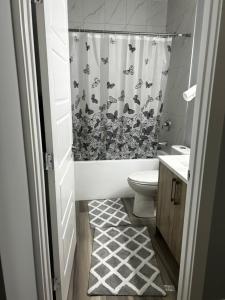 baño con aseo y cortina de ducha con mariposas en Cozy 2bed Guest suite, en Calgary