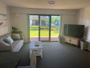 a living room with a couch and a flat screen tv at Nautilus Hamptons Style Beach Apartment Merimbula in Merimbula