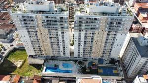 linda vista mar,2 quartos,Ocian SP في برايا جراندي: مبنيان بيض طويلان مع مسبح امامهما