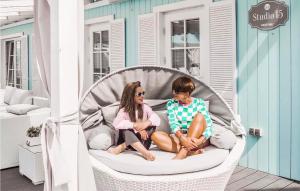 due bambini seduti su una sedia di vimini in veranda di Beautiful Home In Mielno With Wifi a Mielno Altre 15 foto