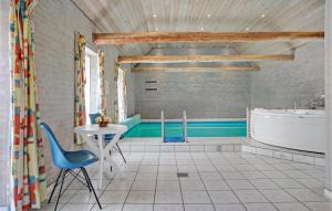 a bathroom with a tub and a table and a chair at Amazing Home In Grenaa With Sauna in Stokkebro
