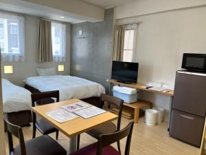a small room with two beds and a table with a table at Across Omoromachi Naha in Naha