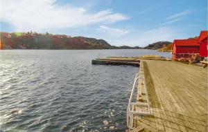 a dock on a lake with a red house at Øyna in Korshamn