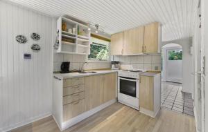 uma cozinha com armários de madeira e electrodomésticos brancos em Two-Bedroom Holiday Home In Ulfborg em Ulfborg