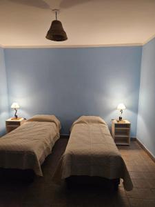 twee bedden in een kamer met blauwe muren en lampen bij La Loma in Salta
