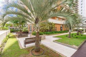 a palm tree in a courtyard with a bench at Dot Home Guanabara - Lindo Apartamento Mobiliado em Campinas in Campinas