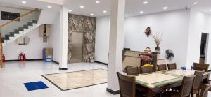 a dining room with a table and chairs and a staircase at HT Hotel in Xuyên Mộc