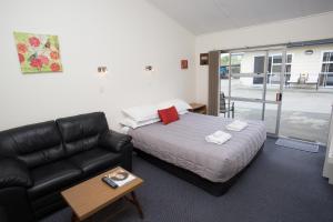 - une chambre avec un lit et un canapé en cuir dans l'établissement The Coast Motel, à Timaru