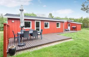 a red cabin with a table and chairs and an umbrella at Alsbo in Sønderho