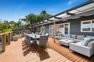 a deck with a couch and a table and chairs at Willowdene pool spa tennis court in Rye