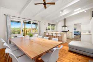 a dining room and kitchen with a wooden table and chairs at Willowdene pool spa tennis court in Rye