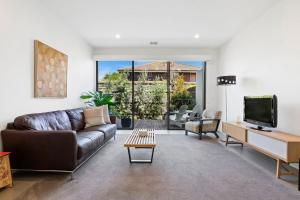 a living room with a leather couch and a tv at Como Villa - Family Retreat Close to Beach & Shops in Parkdale