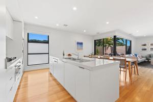 a kitchen with white cabinets and a living room at Como Villa - Family Retreat Close to Beach & Shops in Parkdale +8 photos