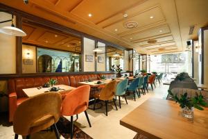a restaurant with wooden tables and chairs and windows at Cicilia City Hotel Saigon Center in Ho Chi Minh City