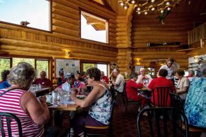 a group of people sitting at tables in a restaurant at Northern Rockies Lodge in Muncho Lake +31 photos