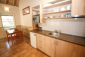 eine Küche mit einem Waschbecken und einem Tisch darin in der Unterkunft Autumn Leaf Cottage 1 in Harrietville + 12 Fotos