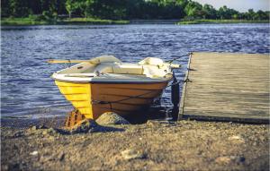 a yellow boat sitting on the shore of a lake at Amazing Home In Fågelmara With Wifi in Fågelmara